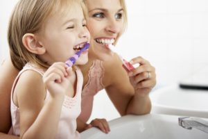 mother and child smiling and brushing their teeth