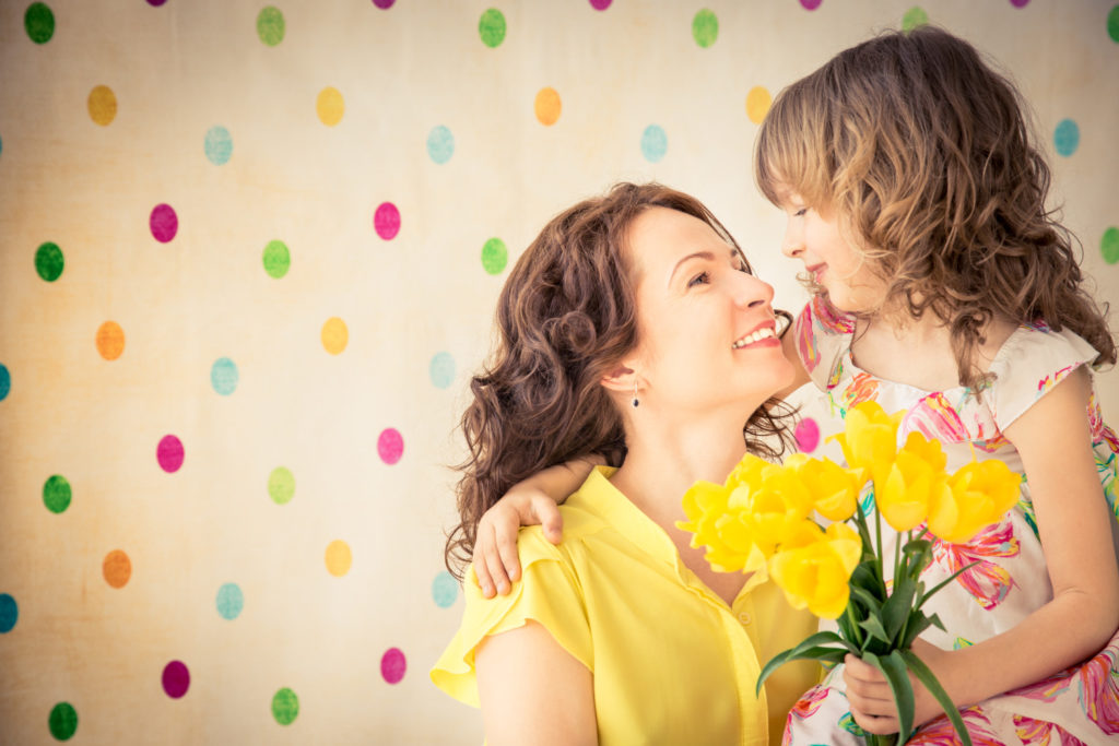 Mother holding her daughter with flowers