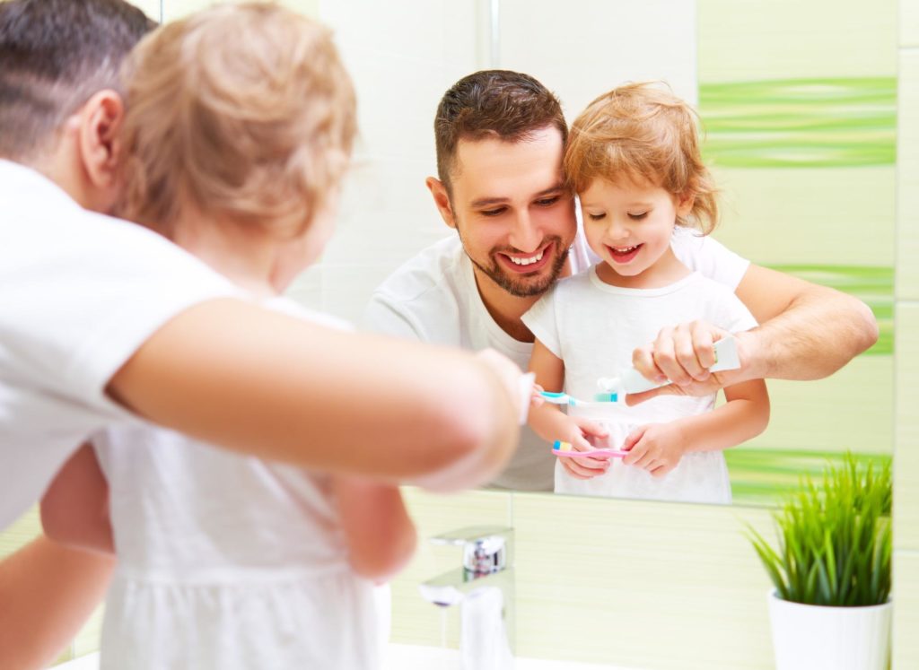 father showing daughter to brush teeth